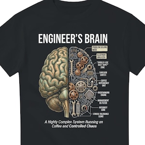 Op de afbeelding: Zwart t-shirt met de tekst "ENGINEER'S BRAIN" en een gedetailleerde afbeelding van een hersenhelft, de ene helft organisch, de andere mechanisch. De afbeelding bevat labels zoals "Coffee Dependency Unit" en "Stress Tolerance (Low)".