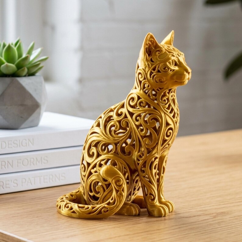 May include: A golden cat figurine with an intricate, openwork design. The cat is in a seated position, with its tail curled around its paws. The decorative sculpture is made of a metallic material and sits on a wooden surface.