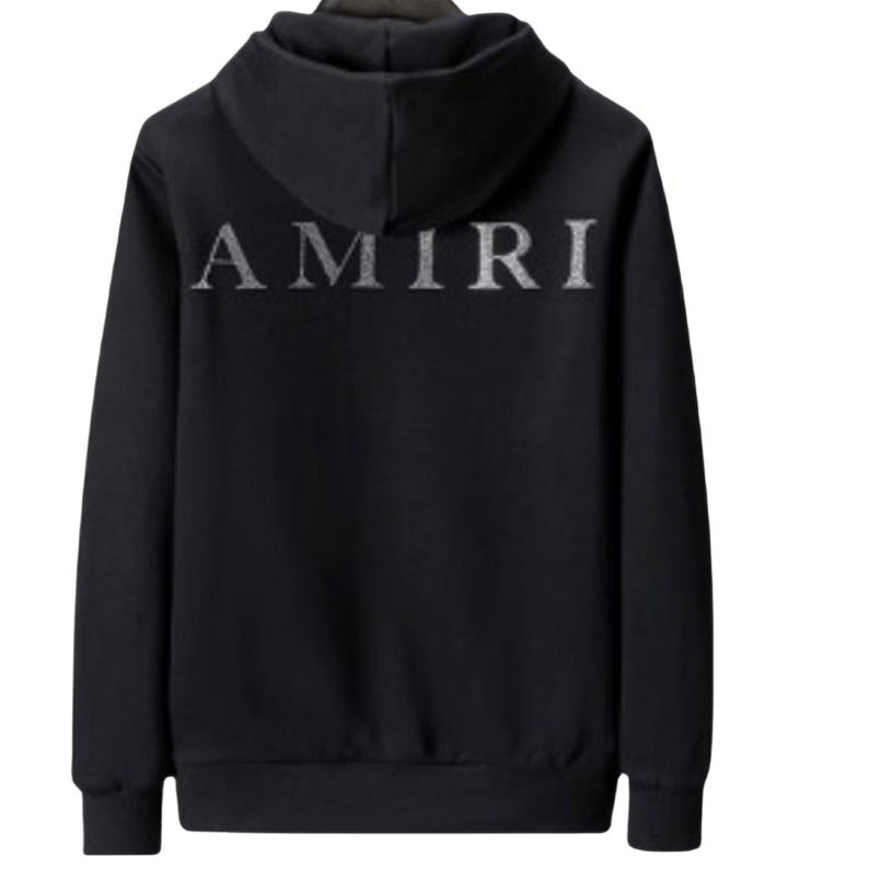 May include: Black hooded sweatshirt with the word "AMIRI" in silver lettering across the back. The sweatshirt has a drawstring hood and a kangaroo pocket. The fabric appears to be a soft material.