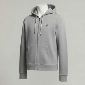May include: A light gray zip-up hoodie with a drawstring hood and a kangaroo pocket. The hoodie features a small navy blue logo on the chest. The garment is displayed on a mannequin against a neutral background.