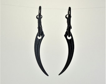 Peut inclure: Une paire de boucles d'oreilles créoles noires avec un design pointu en forme de griffe.