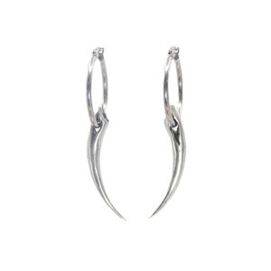 May include: A pair of silver hoop earrings with a sharp, pointed, claw-like design hanging from each hoop.