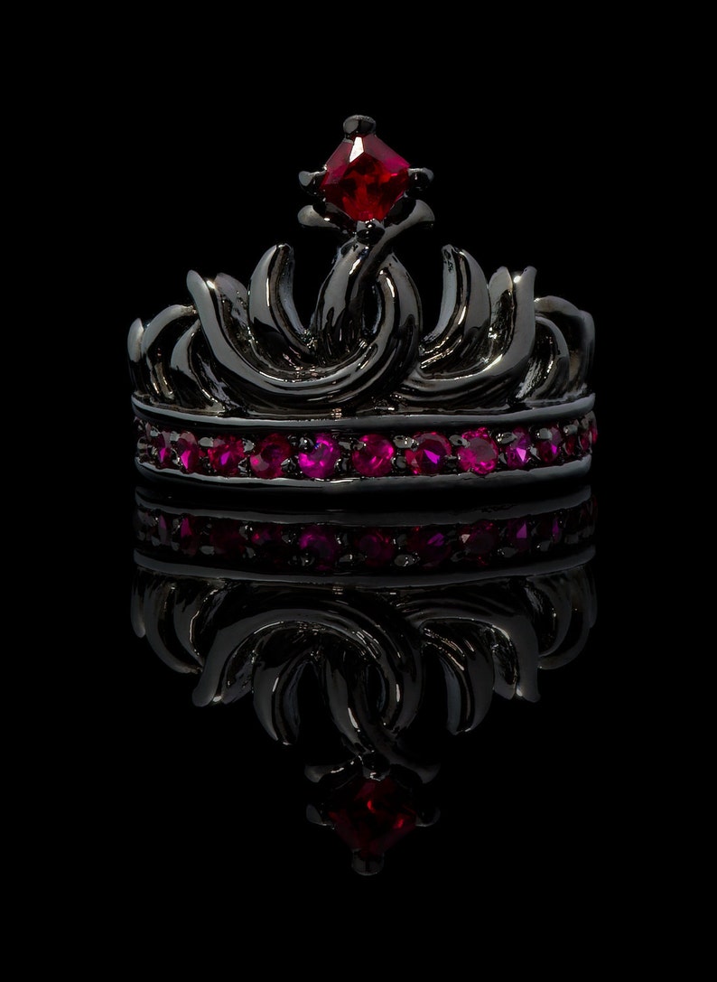 Peut inclure: Une couronne noire avec un bijou rouge sur le dessus et une rang&eacute;e de bijoux roses autour de la base.
