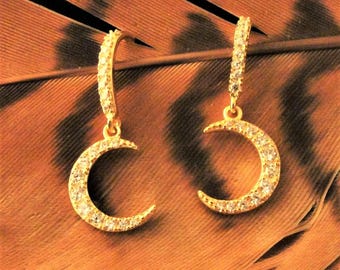 Peut inclure: Une paire de boucles d'oreilles dorées avec un motif de croissant de lune. Chaque boucle d'oreille présente une petite forme de croissant de lune pendante avec des pierres de zircone cubique claires.