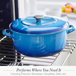 以下が含まれることがあります： 鮮やかなブルーのエナメル鋳鉄製ダッチオーブン。蓋とシルバーのつまみ付き。鍋には両側に取っ手があり、金属製のラックの上に置かれています。下部のテキストには「Performs Where You Need It」と書かれています。