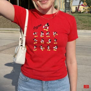 Może przedstawiać: Czerwony t-shirt z ilustracjami Myszki Miki w r&oacute;żnych pozach. Napis "Mickey Mouse" jest wydrukowany u g&oacute;ry po lewej stronie. Koszulka ma kr&oacute;tkie rękawy i jest wykonana z miękkiego materiału.