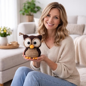 May include: A handmade crochet owl in shades of brown, beige, and yellow. The owl has large, round eyes and a yellow beak. The owl is a decorative item, possibly a toy or home decor piece.