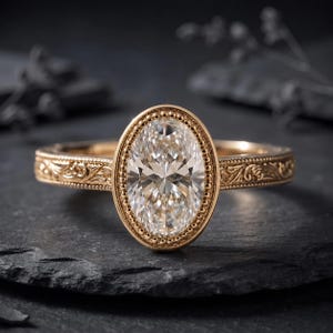 May include: A gold ring featuring a central oval-cut clear gemstone surrounded by a beaded border. The band is crafted from gold and displays intricate engraved scrollwork patterns along the sides, extending from the central setting.