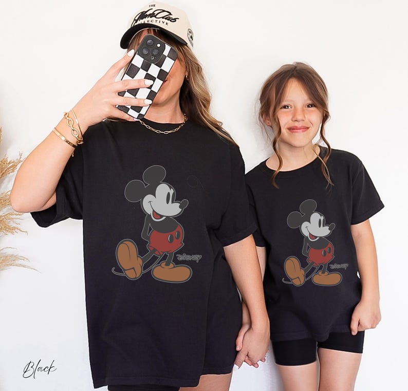 May include: Black t-shirts featuring a classic Mickey Mouse design. The cartoon character is depicted in a walking pose with red shorts, brown shoes, and a gray outline. The word "Disney" is printed below the character. The word "Black" is printed at the bottom left.