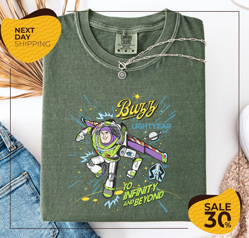 a green t-shirt with a colorful graphic of Buzz Lightyear from the Toy Story franchise, along with the text "Lightyear to Infinity and Beyond". The t-shirt is displayed on a white background, and there are yellow sale signs indicating a 30% discount.