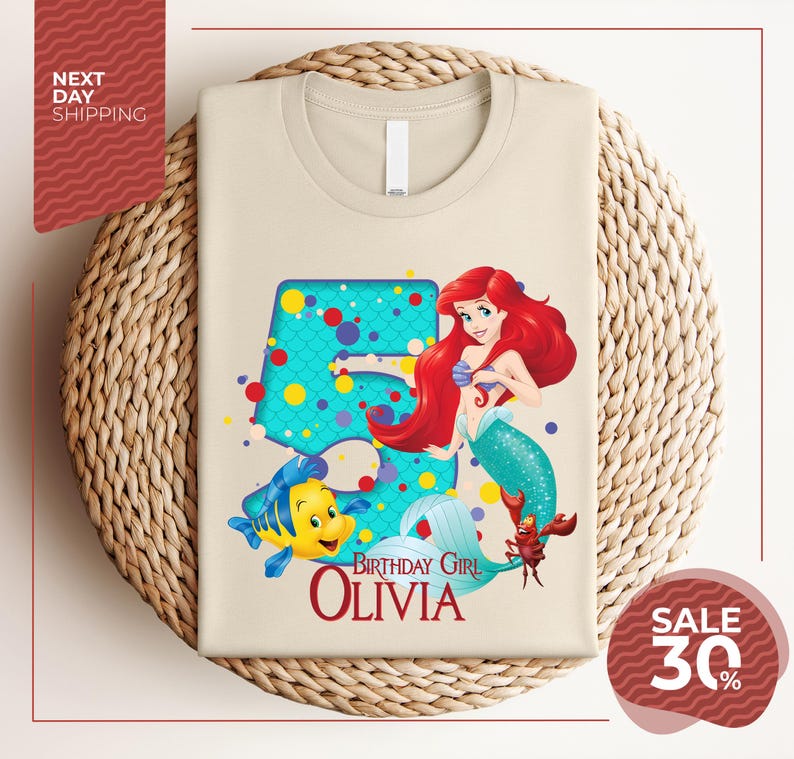 A t-shirt featuring a design of the Disney character Ariel from The Little Mermaid, with the text "Birthday Girl Olivia" and a price of $30.