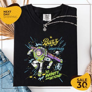 a black t-shirt with a colorful graphic of Buzz Lightyear from the Toy Story franchise, along with the text "Lightyear to Infinity and Beyond". The t-shirt is displayed on a white background, and there are yellow sale signs indicating a 30% discount.