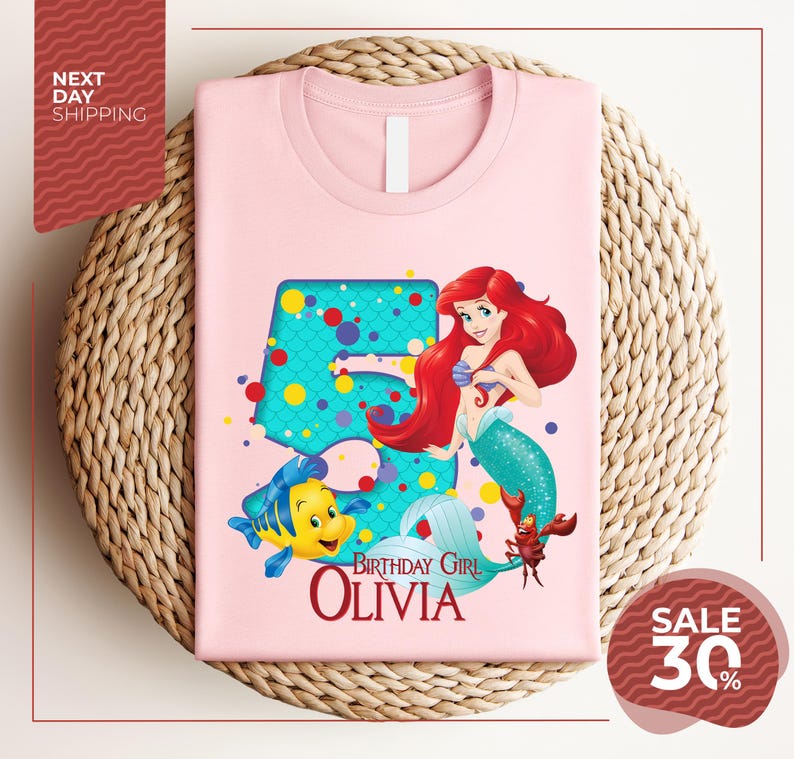 A pink t-shirt featuring a character from the Disney movie "The Little Mermaid" and the text "Birthday Girl Olivia" printed on it.