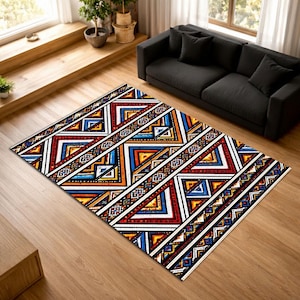 Puede incluir: Una alfombra rectangular con un patrón geométrico. La alfombra presenta un diseño repetitivo de triángulos y líneas en rojo, azul, amarillo y blanco. La alfombra está colocada sobre un suelo de madera, con un sofá negro al fondo.