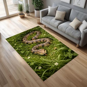 May include: A rectangular rug with a detailed image of a snake in a grassy field. The snake has a brown and tan pattern, with its tongue extended. The rug is surrounded by green grass and small white flowers.