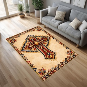 Puede incluir: Alfombra rectangular con un diseño de cruz central en rojo, azul y dorado sobre fondo beige. Borde decorativo con motivos florales y geométricos, ideal para salones.