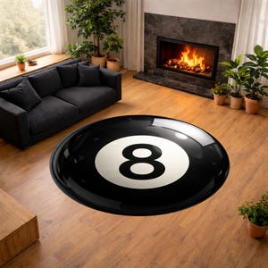 May include: A round black rug with a glossy finish, featuring a large white number 8 in the center, resembling an eight ball. The rug is placed on a hardwood floor in a living room setting.
