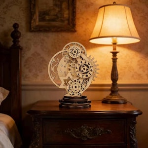 May include: A wooden celestial-themed decorative piece featuring gears, stars, and a crescent moon. The intricate design is made of light-colored wood and sits on a dark wooden base. A lamp with a beige shade is in the background.