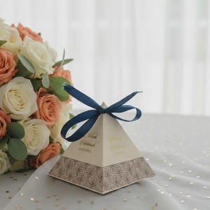 Puede incluir: Una taza de cerámica blanca con un asa negra y el texto "But First, Coffee" en negrita negra. La taza está sobre un fondo borroso. La taza mide aproximadamente 10 cm de altura.