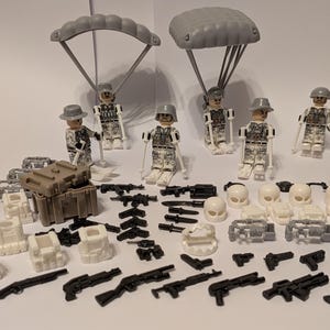 May include: A collection of toy military figures and accessories. The set includes soldiers with parachutes, rifles, helmets, and a brown dog figurine. There are also various weapons, crates, and other gear in the image.