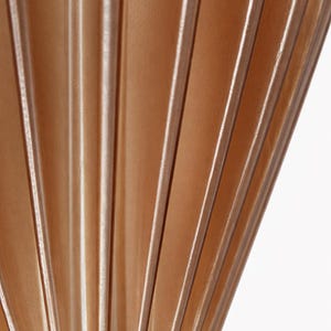 Pode incluir: Close-up de um tecido plissado em um tom marrom claro e quente. O tecido tem dobras verticais com destaques sutis, criando um padr&atilde;o texturizado em forma de leque. O fundo &eacute; branco.