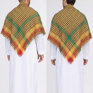 May include: A patterned scarf with a fringed edge, draped over a white garment. The scarf features a plaid design in shades of green, yellow, red, and brown. The image shows two people wearing the scarf.