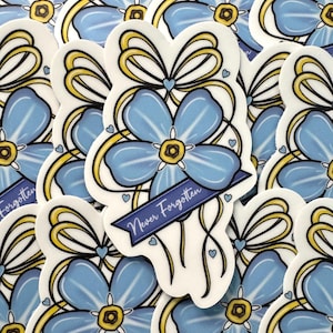 May include: A die-cut sticker featuring a light blue five-petaled flower with a yellow center, accented by a yellow ribbon bow at the top and a dark blue banner across the bottom with the white text Never Forgotten, surrounded by small hearts.