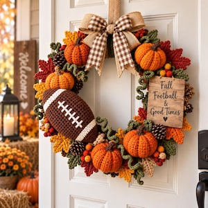 May include: A decorative autumn wreath featuring crocheted orange pumpkins, a brown crocheted football, pinecones, and fabric leaves. A brown and white gingham bow sits at the top. A wooden sign reads: Fall Football & Good Times.