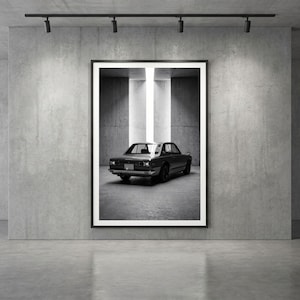 Peut inclure: Une impression d'art encadrée en noir et blanc représentant la vue arrière d'un coupé vintage garé dans un espace en béton avec un faisceau lumineux vertical éclairant le véhicule par l'arrière, exposé dans une galerie.