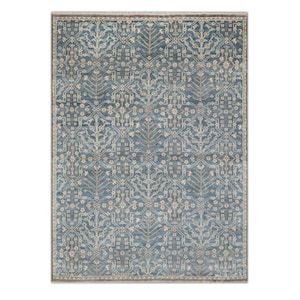 May include: A rectangular area rug featuring a deep blue background with a repeating cream-colored geometric and floral pattern. The design includes stylized tree motifs arranged in a grid, finished with a thin, neutral-toned border and fringe.