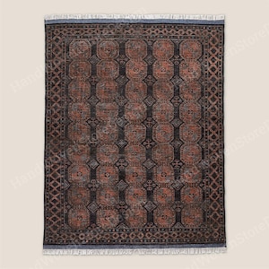 Peut inclure: Tapis rectangulaire avec un motif géométrique dans les tons de marron, noir et gris. Le tapis présente un motif répétitif de carrés et d'octogones, avec une bordure en forme de losanges. Les bords ont une frange.
