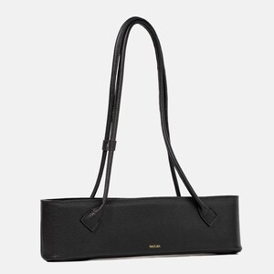 May include: A black, horizontally elongated shoulder bag with a pebbled leather texture. The bag features two long, thin, matching black shoulder straps and the brand name TAKSUBA printed in small gold lettering on the front lower center.