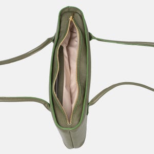 May include: An olive green tote bag with a textured exterior, featuring two long shoulder straps and a central gold-toned zipper closure. The interior is lined with a light beige fabric, revealing a single main compartment and a side pocket.