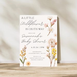 May include: A baby shower invitation with floral accents. The text reads "A Little Wildflower Is On Its Way" and invites guests to Savannah's Baby Shower on 6.22.26 at 2 PM. Includes RSVP and registry information.