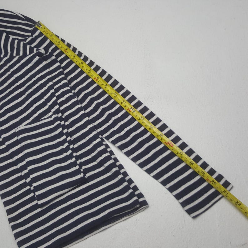 May include: Navy blue and white striped long-sleeve shirt. A yellow measuring tape is laid across the sleeve, showing a length of approximately 22 inches. The shirt has a classic nautical design.