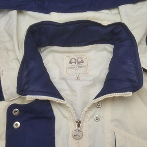 Pode incluir: Casaco creme com detalhes em azul marinho. O casaco tem fecho de correr, bot&otilde;es de press&atilde;o e gola. O log&oacute;tipo da marca "courr&egrave;ges paris" &eacute; vis&iacute;vel numa etiqueta dentro da gola. Tamanho 9.