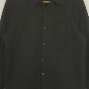 May include: A white ceramic mug with a black handle and the text "But First, Coffee" in a handwritten style. The mug is on a white surface. The mug is approximately 4 inches tall.