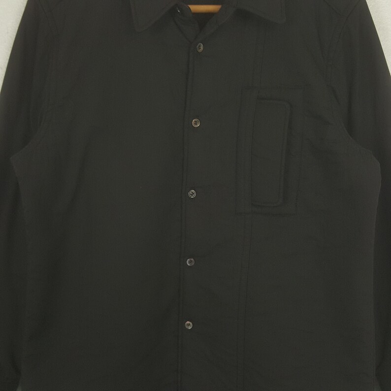 May include: A white ceramic mug with a black handle and the text "But First, Coffee" in a handwritten style. The mug is on a white surface. The mug is approximately 4 inches tall.