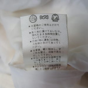 Pode incluir: Uma etiqueta de tecido branco com texto japon&ecirc;s e s&iacute;mbolos de cuidados. A etiqueta inclui s&iacute;mbolos para limpeza a seco, lavagem e secagem. O texto fornece orienta&ccedil;&otilde;es de lavagem e secagem.
