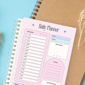 Peut inclure: Une page de planificateur quotidien avec un fond quadrillé rose clair, comprenant un emploi du temps de 7h00 à 21h00, des sections pour la date, le mois, les rappels, les objectifs, les priorités et des notes. Le texte Daily Planner est en haut.
