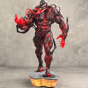 Könnte beinhalten: Detaillierte Figur einer muskulösen, rot-schwarzen Figur mit langer, roter Zunge und klauenartigen Händen. Die Figur steht auf einem grau-gelben Sockel mit strukturierter Oberfläche. Das Design der Figur ist sehr detailliert.