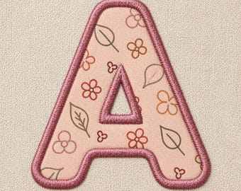 Puede incluir: Parche bordado con la letra "A" y un diseño floral. La letra es de color rosa claro con un borde rosa oscuro. El patrón floral incluye flores y hojas marrones y rosas.