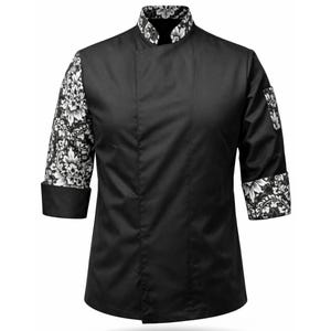 May include: Black chef coat with floral patterned sleeves and collar. The coat features a mandarin collar, three-quarter sleeves, and a single-breasted design. The floral pattern is in black and white.