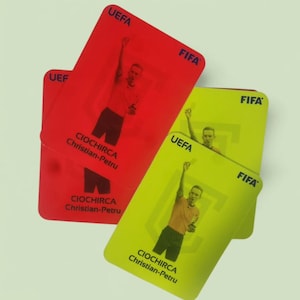 以下が含まれることがあります： FIFAとUEFAのロゴが入った赤と黄色のサッカー審判カード。各カードには審判の画像とCIOCHIRCA Christian-Petruの名前が記載されています。