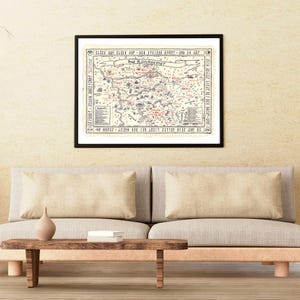 Könnte beinhalten: Ein gerahmter Karten-Druck mit schwarzem Rahmen, der über einem Sofa hängt. Die Karte ist in Schwarz-, Rot- und Beigetönen gehalten, mit Text auf Deutsch. Die Karte trägt den Titel "Das Ruhrgebiet". Das Sofa ist beige, mit einem Holztisch und einer Vase.