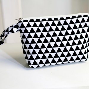 Puede incluir: Bolsa de cremallera con estampado geométrico en blanco y negro con asa.