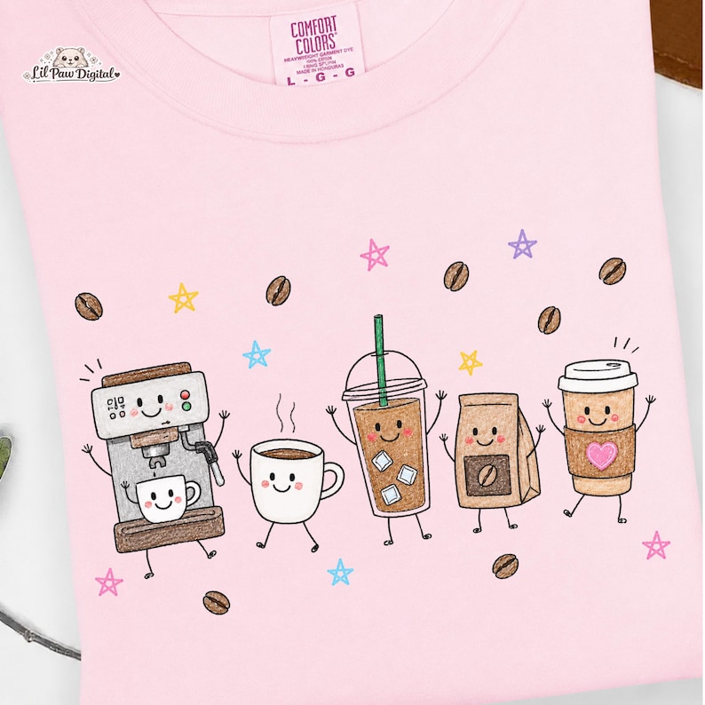 May include: A light pink t-shirt featuring a graphic print of five anthropomorphic coffee-themed characters including an espresso machine, a mug, an iced coffee, a coffee bag, and a paper cup, surrounded by coffee beans and colorful stars.