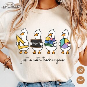 Puede incluir: Camiseta beige con un diseño caprichoso de cuatro gansos de dibujos animados, cada uno sosteniendo elementos relacionados con las matemáticas como una regla, una pizarra, libros y un gráfico circular. El texto "just a math teacher goose" está escrito debajo.