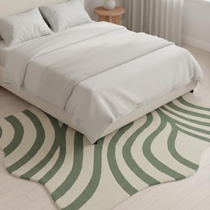 May include: A bedroom scene featuring a white bed with white bedding and pillows. A green and white striped rug is placed at the foot of the bed. The rug has a unique, organic shape. A small potted plant is in the background.
