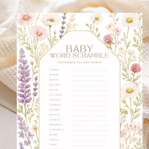 May include: A rectangular baby word scramble game card featuring a floral border of pink, white, and purple wildflowers. The center contains the text BABY WORD SCRAMBLE, UNSCRAMBLE THE BABY WORDS!, and a list of scrambled words with blank lines.